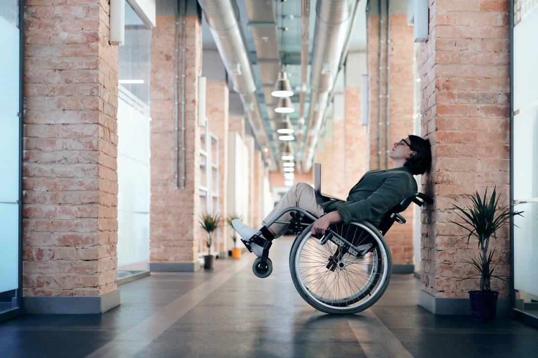 Woman in a wheelchair rocking it back at an angle while leaning against a wall.