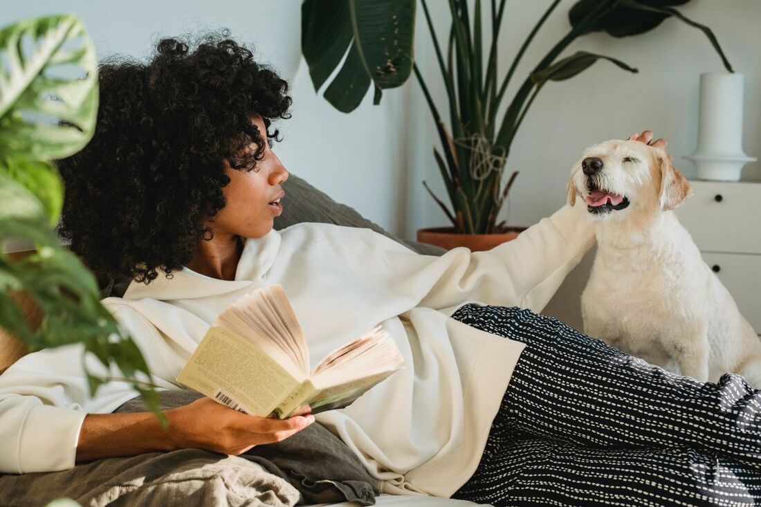Woman reading a book while petting her dog