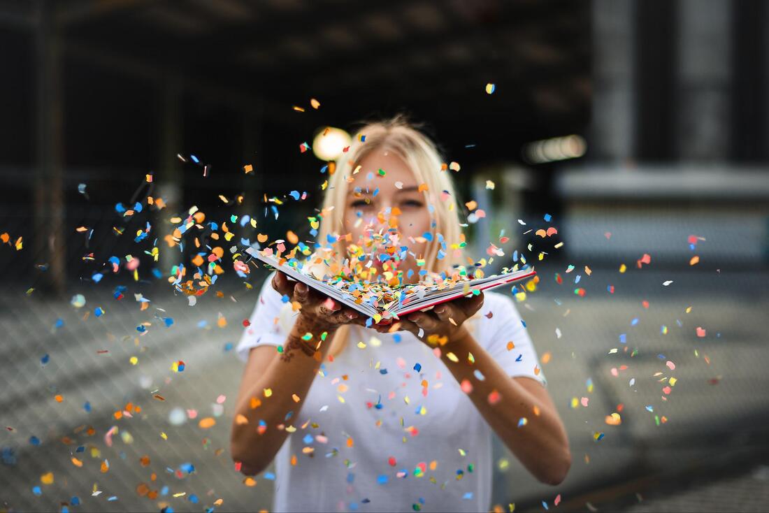 Woman blowing confetti from an open book